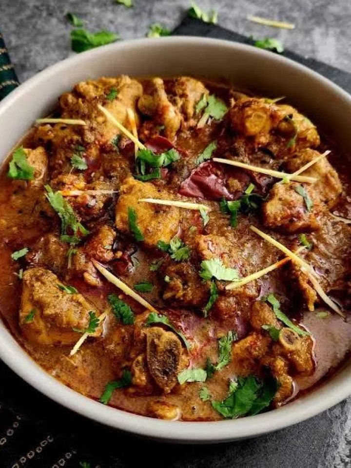Copper karahi of chicken achari in a golden spiced gravy with green chillies, ginger and coriander, served with roti and raita