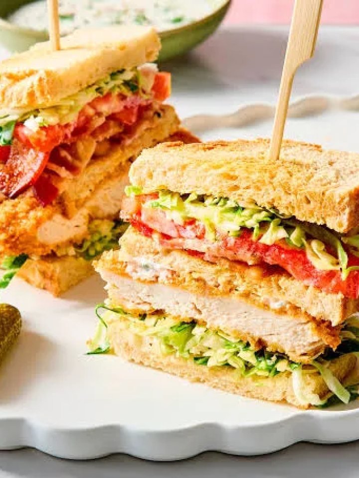 Chicken club sandwich cut into triangles showing layers of chicken, bacon, egg, tomato and lettuce on toasted bread