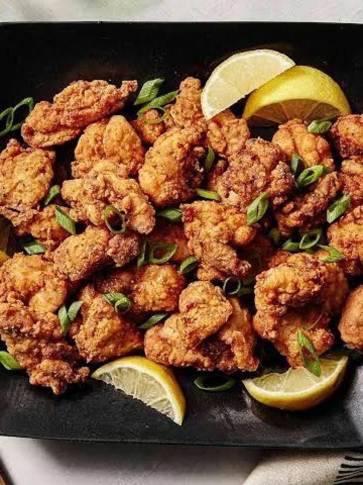 Plate of golden crispy chicken karaage with lemon wedges, mayonnaise and shredded cabbage