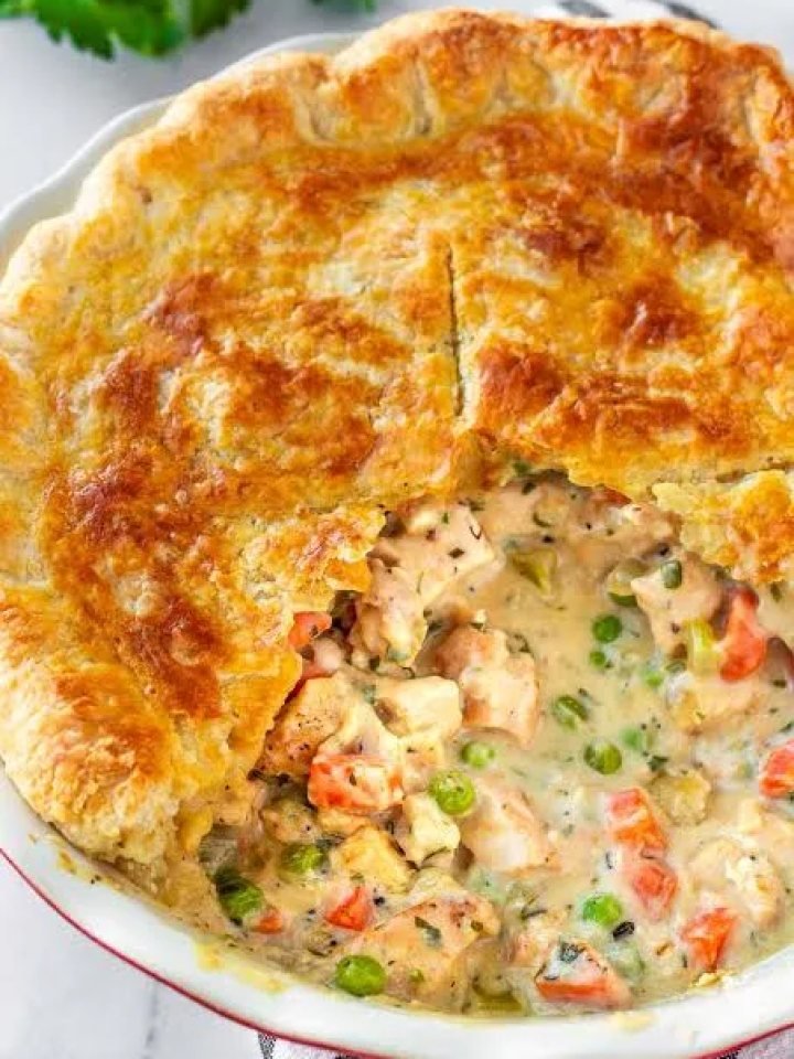 Golden chicken pot pie with a slice removed showing creamy chicken and vegetable filling