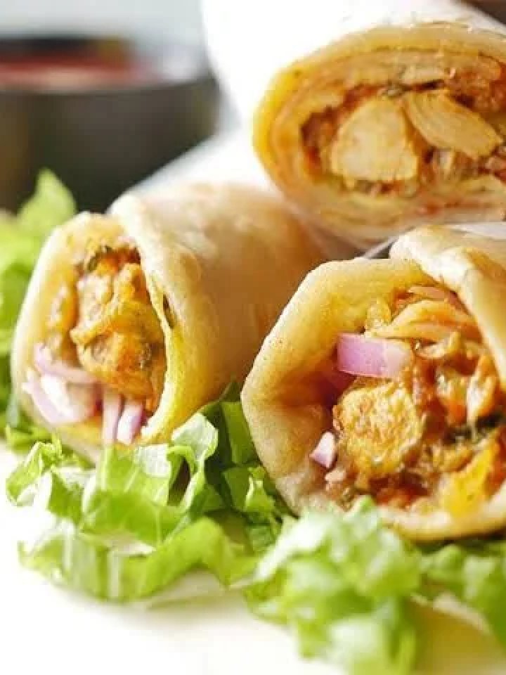 Chicken roll parathas with one cut open to show spiced chicken, mint yogurt sauce and onions