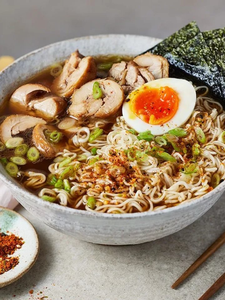 Bowl of chicken shoyu ramen with soy egg, shredded chicken, spinach, sweetcorn and nori in clear brown broth
