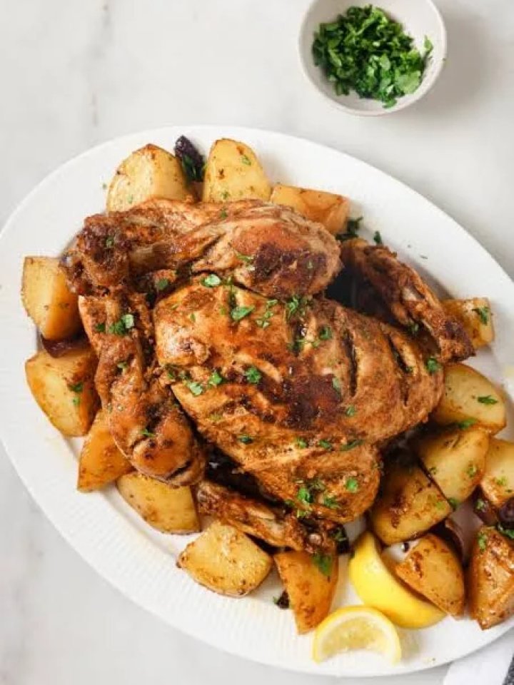 Golden roasted chicken pieces on a tray with onion gravy, green chillies and lemon wedges
