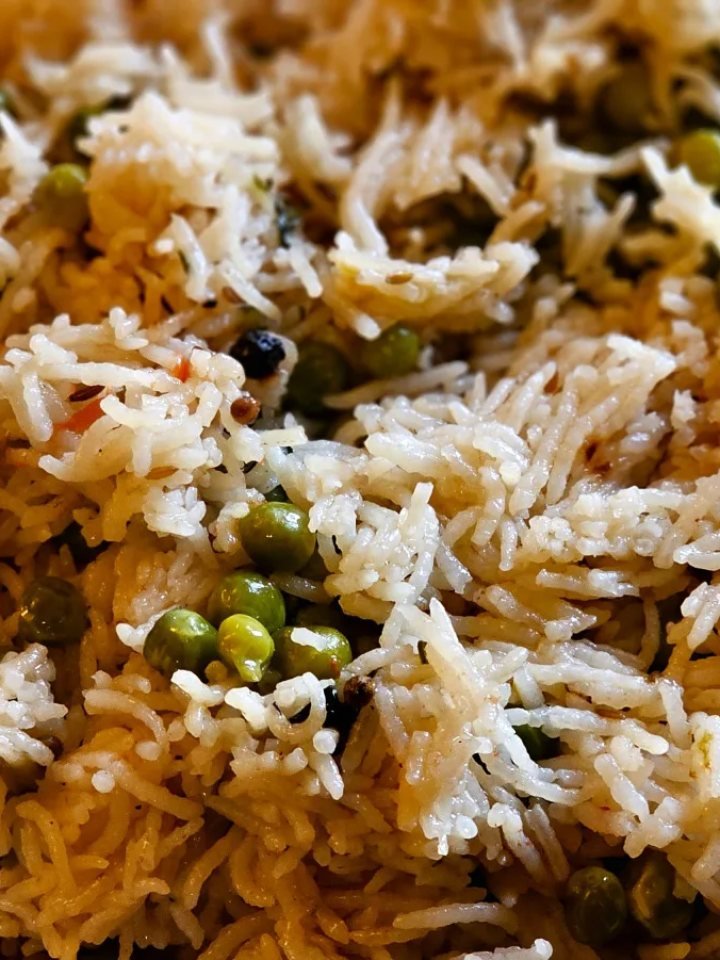 Golden chicken yakhni pulao topped with fried onions and mint, served in a wide dish with raita and salad