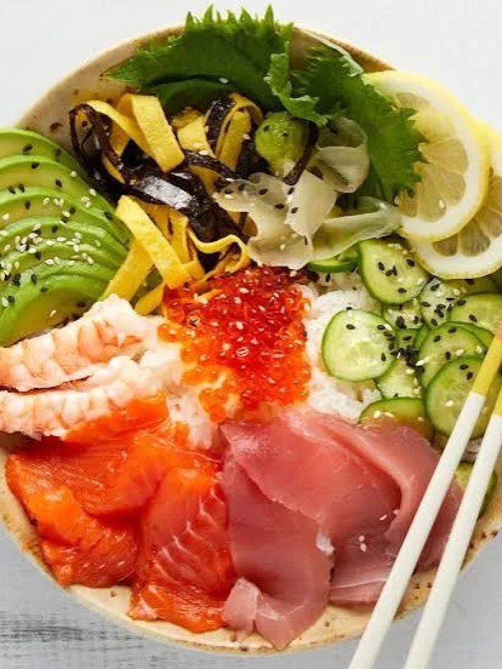 Chirashi sushi bowl topped with salmon, prawns, egg ribbons, cucumber and avocado over sushi rice