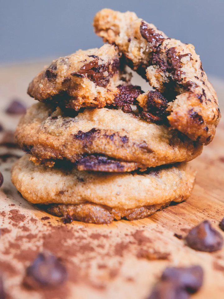 Chewy chocolate chip cookies on a wooden board with a glass of milk