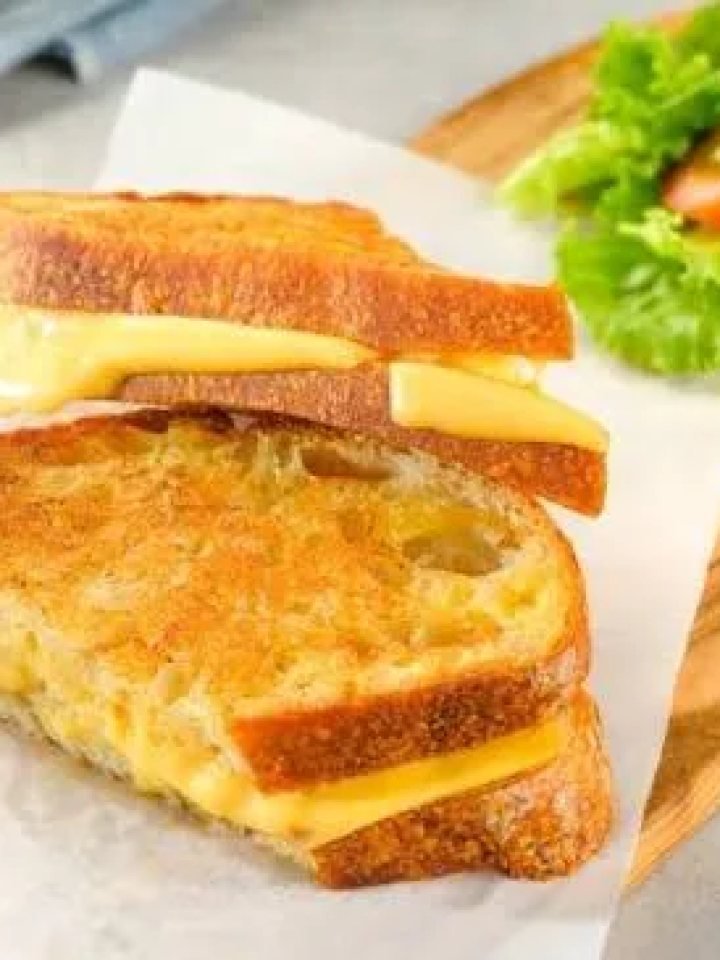 Grilled cheese sandwich cut in half with melted cheese stretching between the golden toasted halves