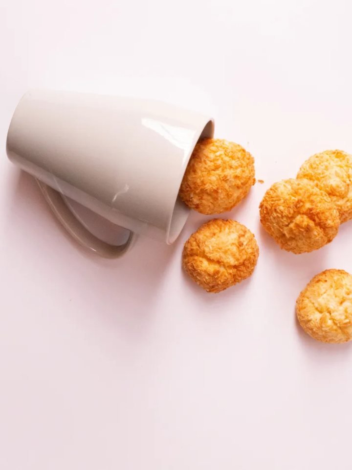 Golden coconut macaroons, some dipped in dark chocolate, on a white plate