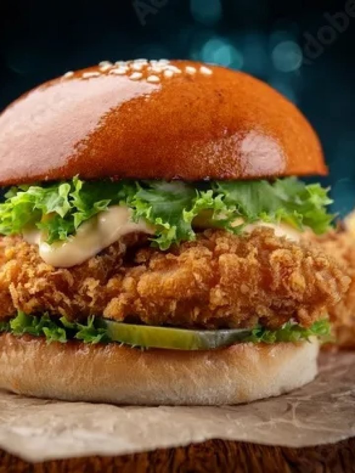 A crispy fried chicken burger with lettuce, tomato and pickles in a toasted bun, served with fries