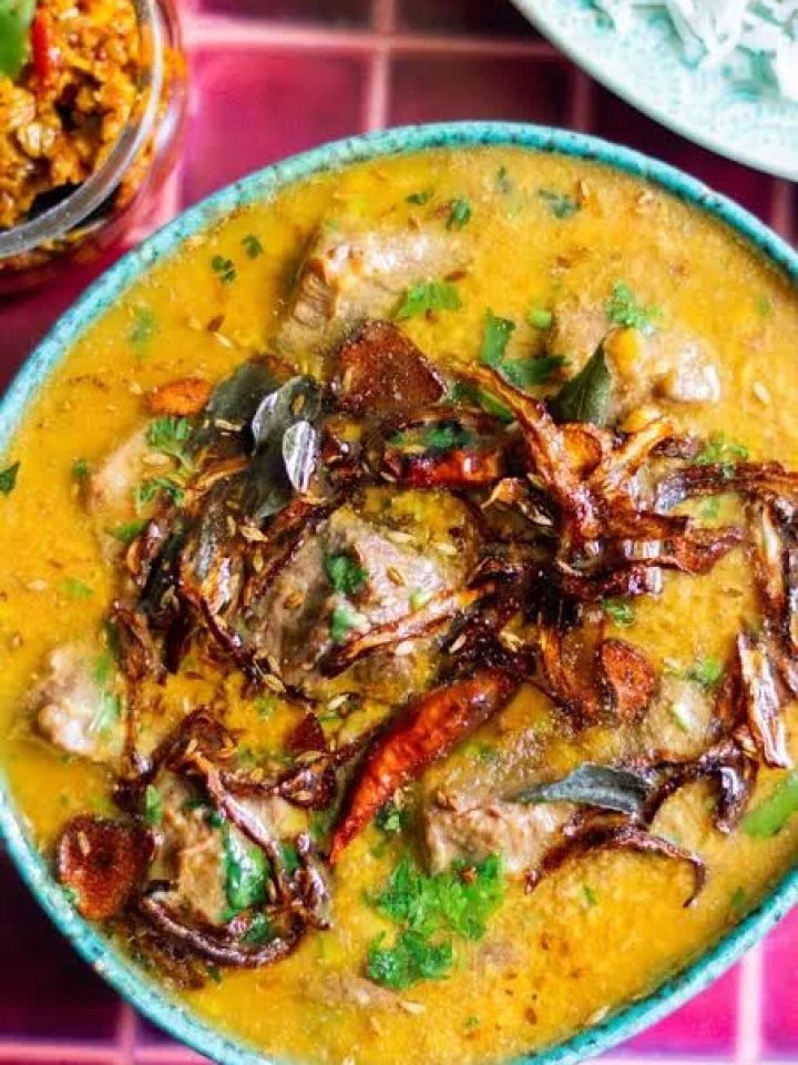 A pot of Pakistani daal gosht with mutton pieces, garnished with coriander, ginger and garlic tarka, served with roti