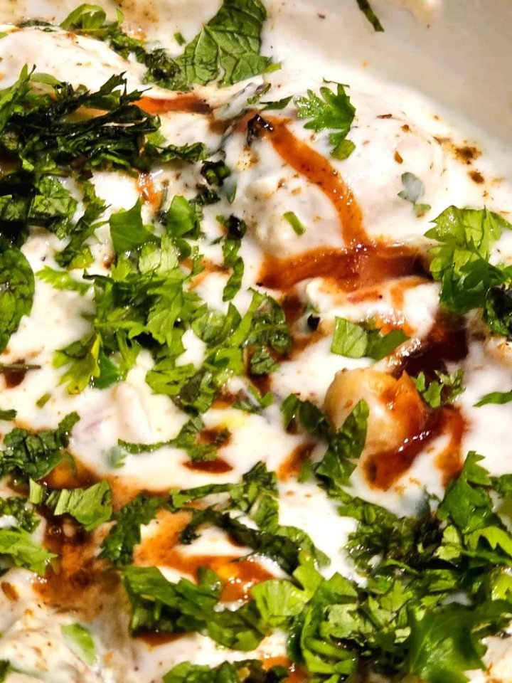 A dish of Dahi Baray with lentil fritters in yogurt, tamarind chutney, spices and pomegranate seeds