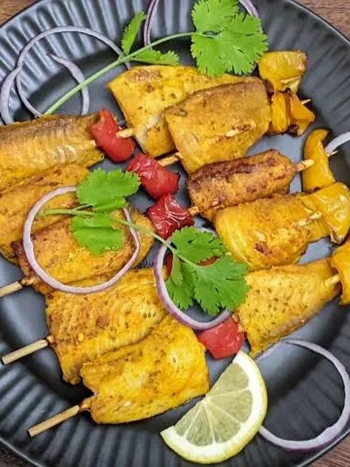 Skewers of golden-red grilled fish tikka with capsicum and onion, served with lemon wedges and mint chutney