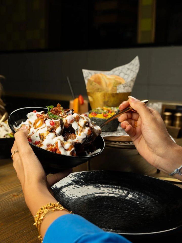 Bowl of Pakistani fruit chaat with apple, guava, grapes, orange, banana and pomegranate topped with mint and chaat masala