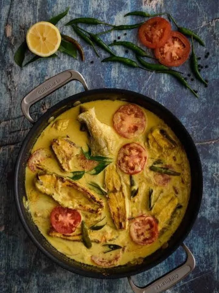 Pan of Kerala fish moilee with white fish pieces in creamy coconut sauce, green chillies and curry leaves