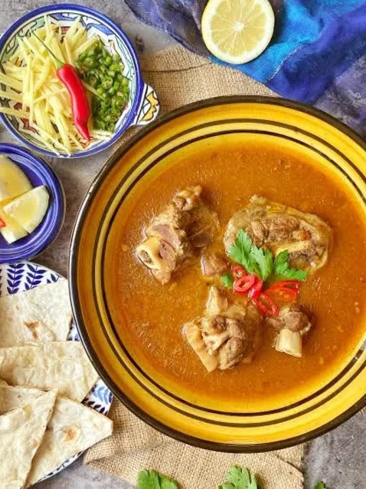 A clay pot of rich Kunna Gosht mutton curry topped with ginger and coriander, served with naan