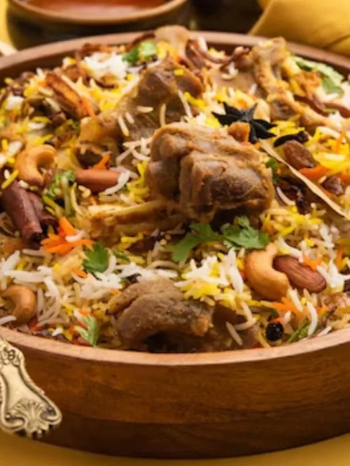 Copper pot of Lucknowi mutton biryani with saffron rice, mutton pieces, fried onions and fresh herbs