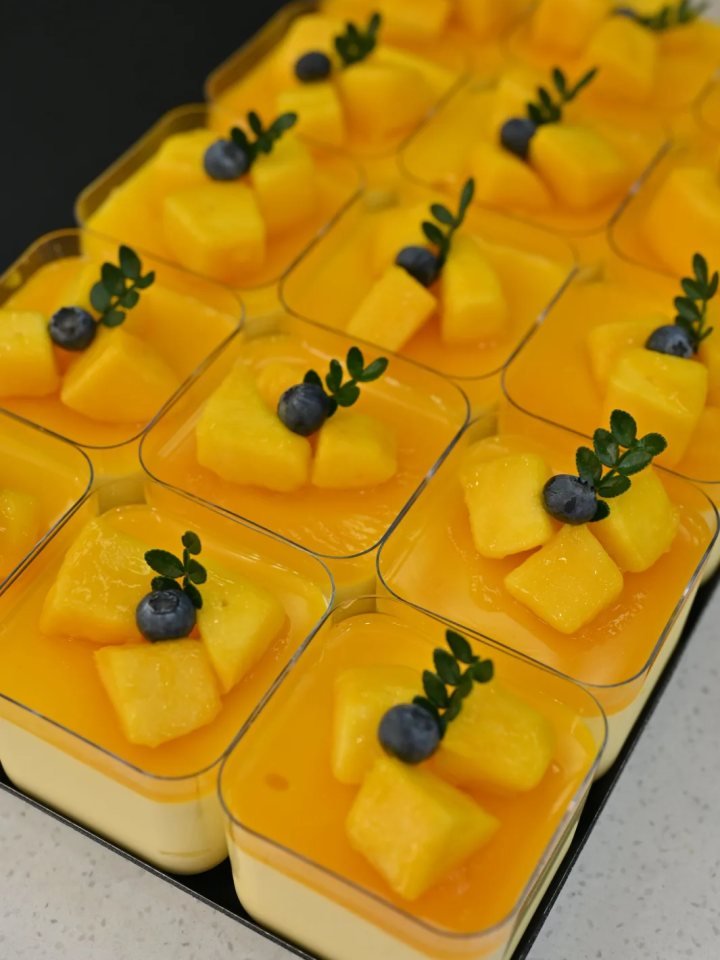 Glasses of smooth golden mango mousse topped with diced mango and mint leaves