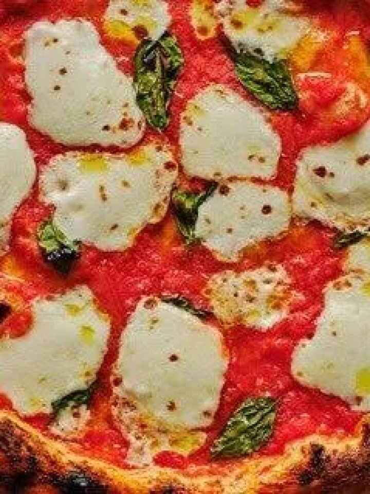 Margherita pizza with melted mozzarella and fresh basil on a wooden board