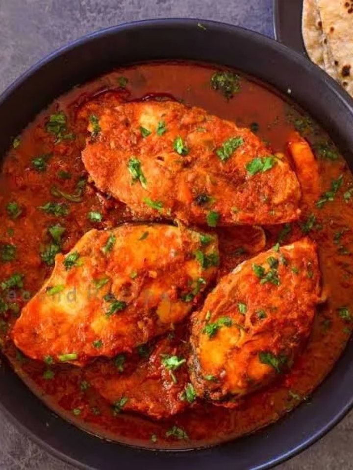 Pan of Pakistani masala fish curry with fish steaks in red tomato gravy, green chillies and fresh coriander, served with rice