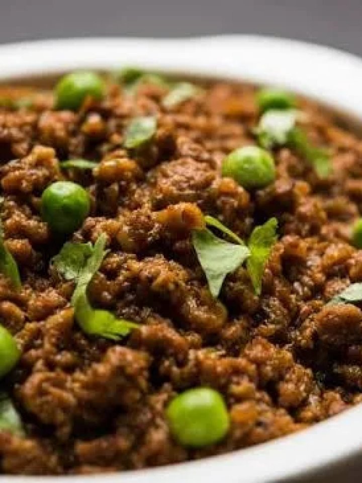 Pot of matar keema with beef mince and green peas, garnished with coriander and ginger, served with roti