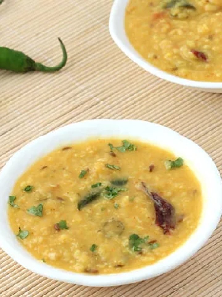Bowl of golden moong daal topped with garlic tarka, red chillies and fresh coriander, served with rice and roti