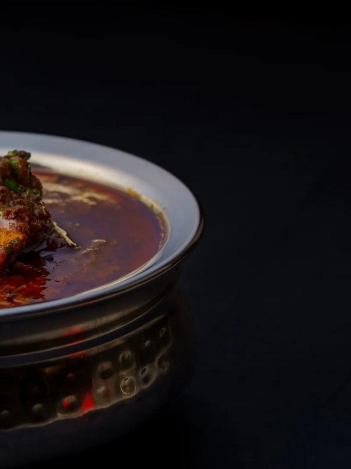 A karahi of mutton in a thick red tomato masala, garnished with ginger, green chillies and fresh coriander, served with naan.