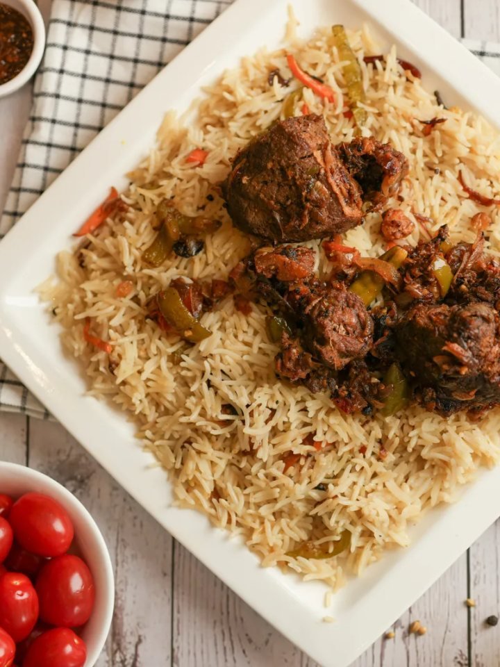 A pot of mutton yakhni pulao with golden basmati rice, mutton pieces, fried onions and mint