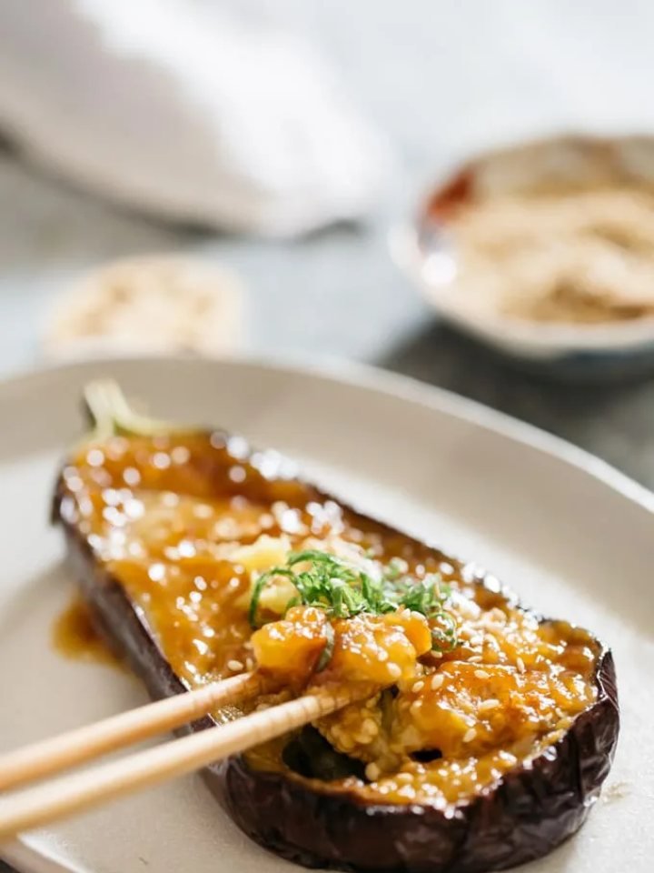 Miso-glazed aubergine halves topped with sesame seeds and spring onions, served with steamed rice