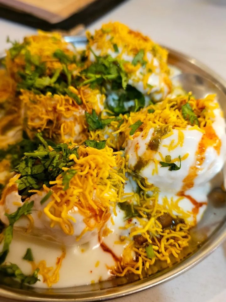 Platter of papri chaat topped with chickpeas, yogurt, chutneys, sev and pomegranate seeds