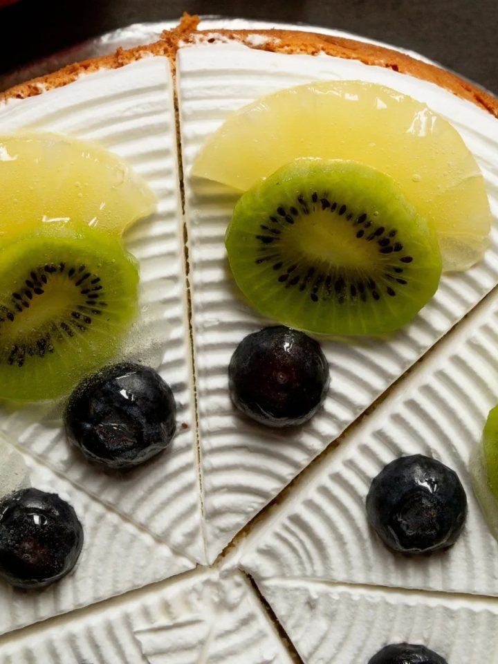 Pineapple upside-down cake with glossy caramelised pineapple rings and cherries, with one slice cut