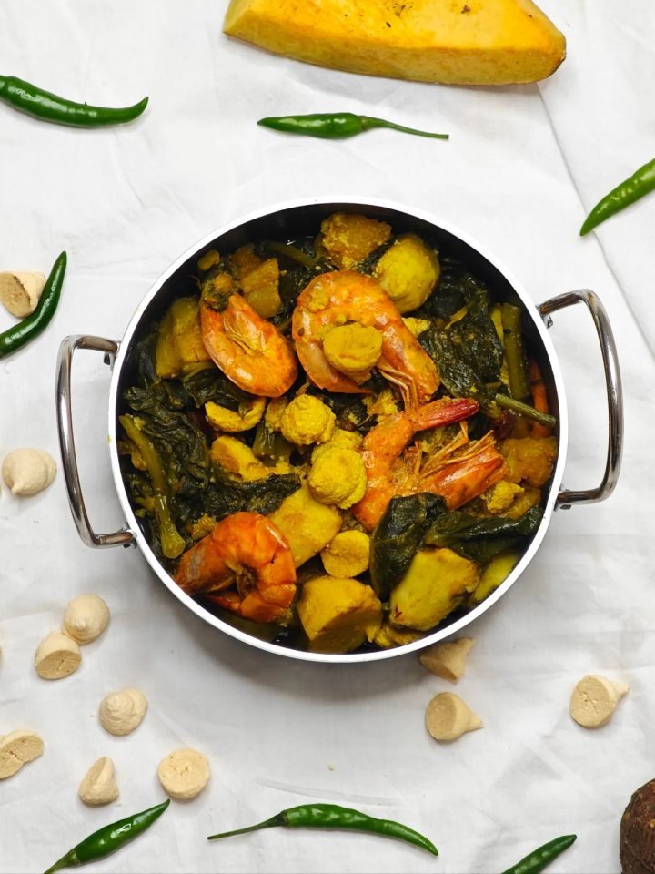 A karahi of prawns in thick tomato masala garnished with ginger and coriander, served with naan and lemon
