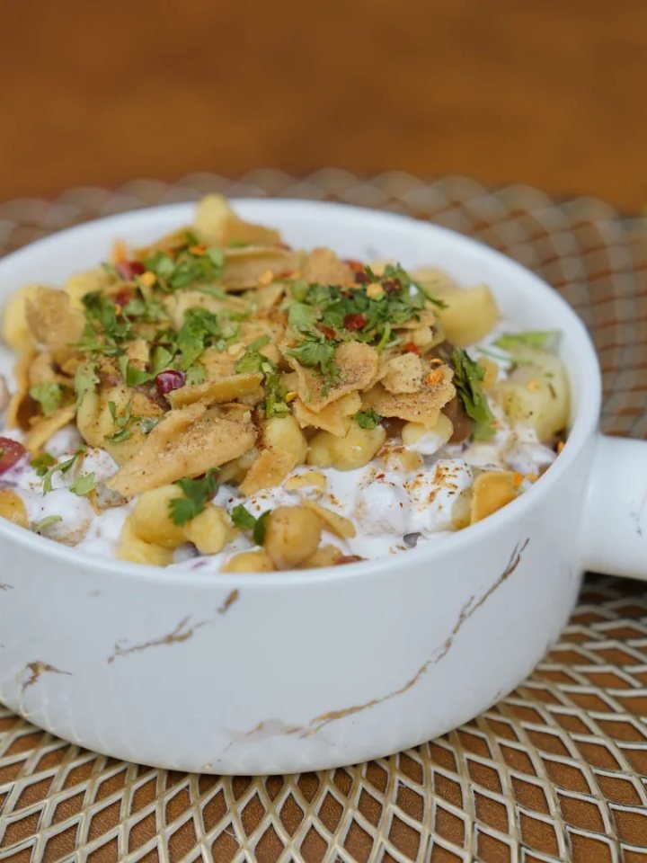 A bowl of sabudana khichdi with tapioca pearls, potato, peanuts and coriander beside a lemon wedge