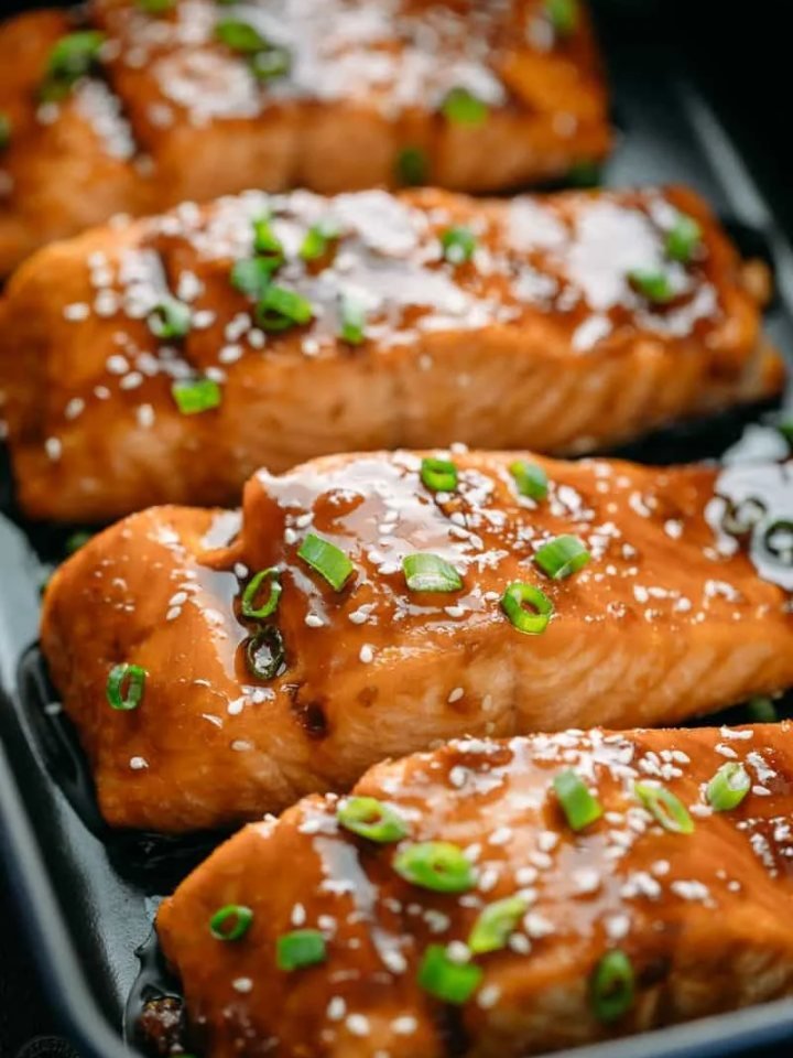 Glazed teriyaki salmon fillet over steamed rice with broccoli, sesame seeds and spring onions
