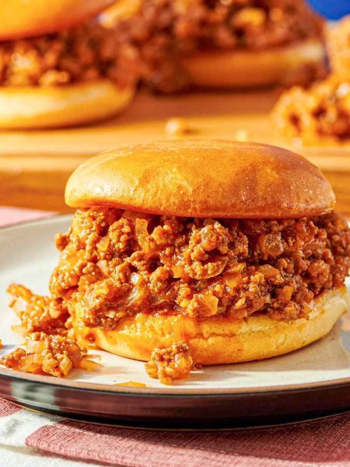 Sloppy Joe sandwiches with saucy beef filling on toasted buns served with pickles and potato wedges