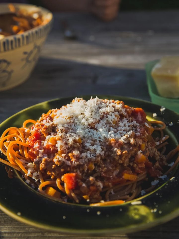 A bowl of spaghetti topped with rich beef and tomato Bolognese sauce, grated Parmesan and fresh basil