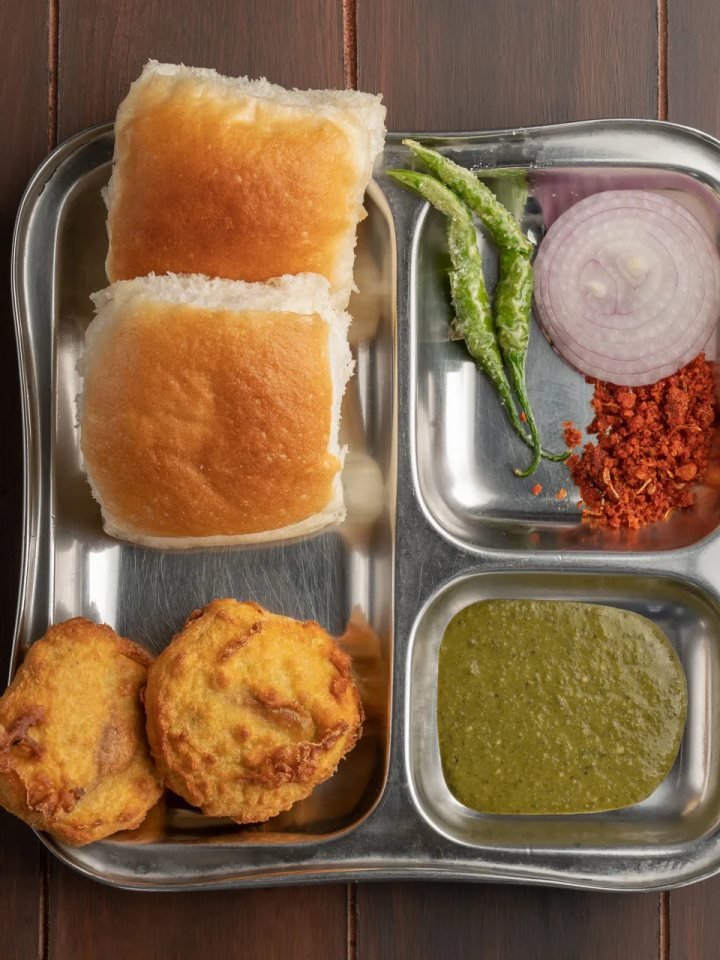 Vada pav with golden potato fritters in toasted buns, green chutney and fried green chillies