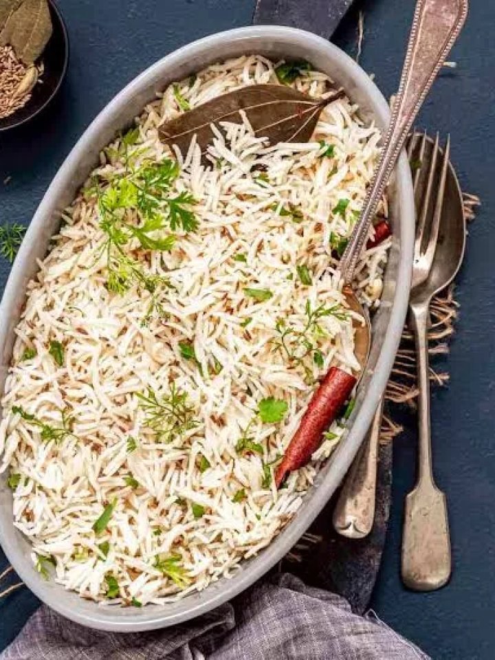 A bowl of fluffy zeera rice with visible cumin seeds and fresh coriander